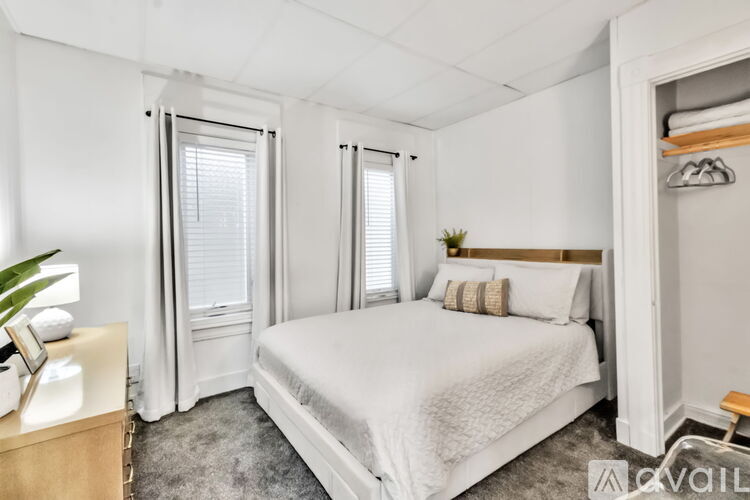 A bedroom with a large bed, a nightstand, and a window with blinds.