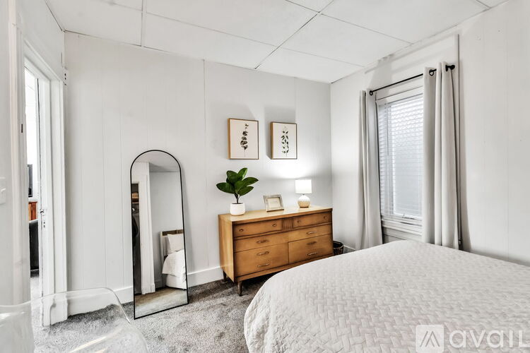 A bedroom with a large bed, a dresser, and a mirror.