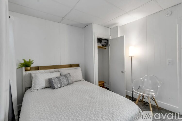 A bedroom with a bed, chair, and lamp.