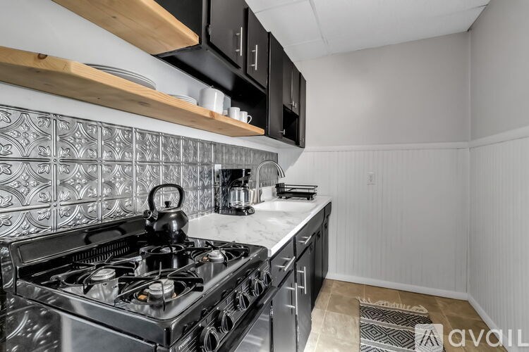 A kitchen with a black stove top oven and a black microwave above it.