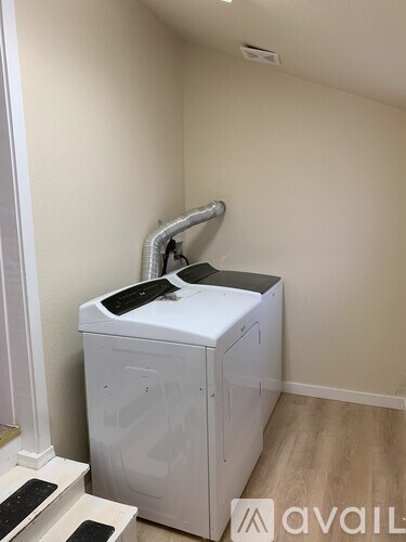 A white dryer is in a room with a wall-mounted vent.