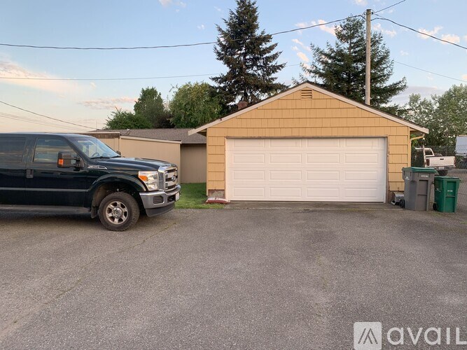 A black truck is parked in a driveway next to a garage.