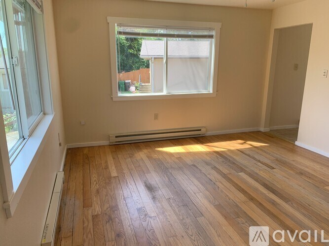 A room with wooden flooring and a window showing an outdoor view.