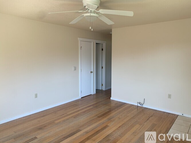 A room with a ceiling fan and wooden flooring.