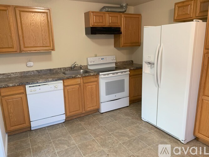 A kitchen with white appliances and wooden cabinets.