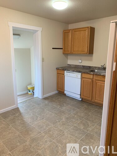 A kitchen with wooden cabinets and a white dishwasher.
