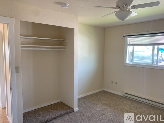 A room with a ceiling fan and a window with blinds.