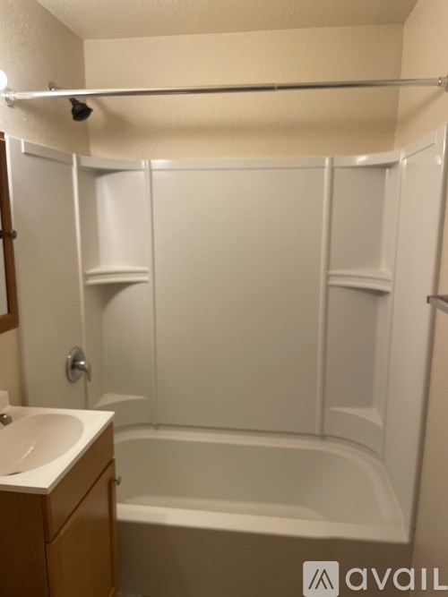 A white bathroom with a tub, sink and shelves.