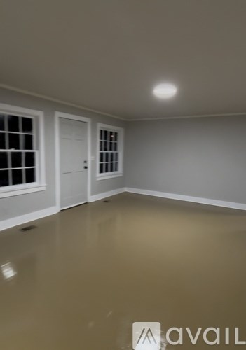 A room with a brown floor and white walls.