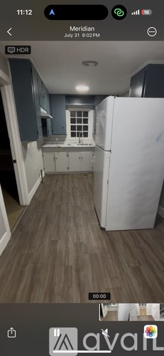 A kitchen with a white refrigerator and wooden flooring.