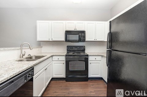A kitchen with black appliances and white cabinets.