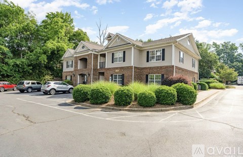 A large brick house with a parking lot in front.