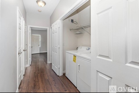 A long hallway with white doors and a washer and dryer in the corner.