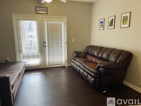 A brown leather couch sits in a room with a sliding glass door.