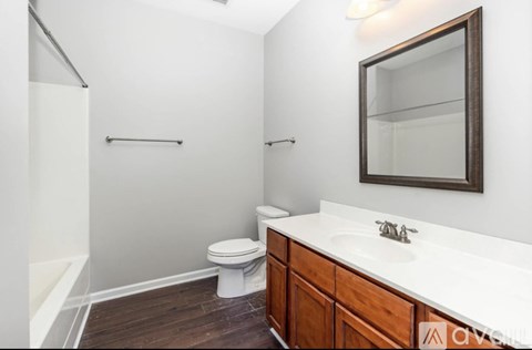 A white toilet sits in a bathroom with a wooden vanity and a mirror.