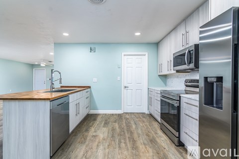 A kitchen with a wooden counter top and stainless steel appliances.