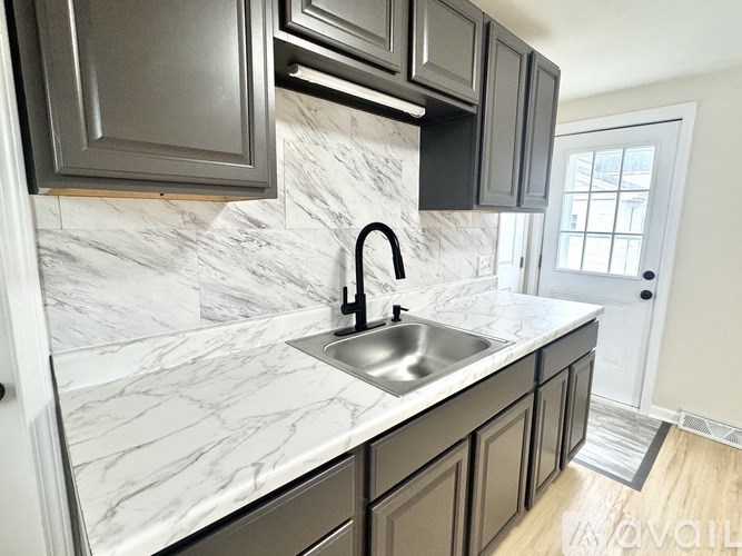 A kitchen with a marble countertop and dark cabinets.