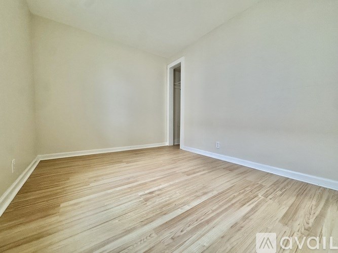 A room with wooden flooring and a doorway leading to another room.