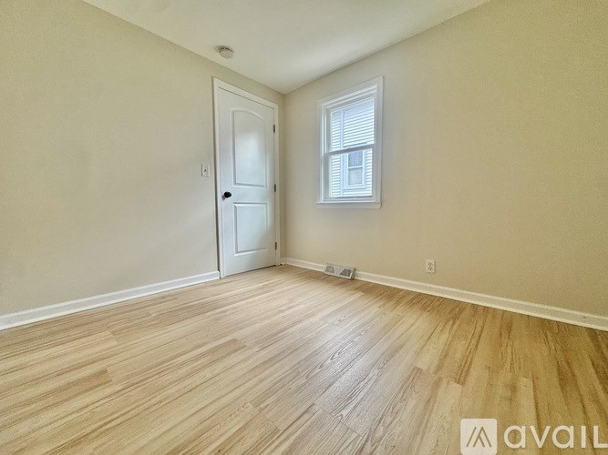 A room with a door and a window with wooden flooring.