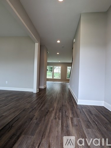 A long hallway with wood floors and white walls.
