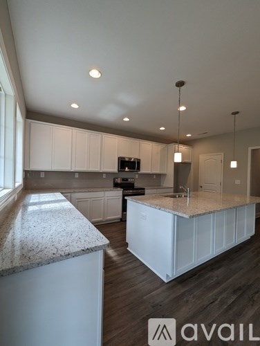 A modern kitchen with white cabinets and a granite countertop.
