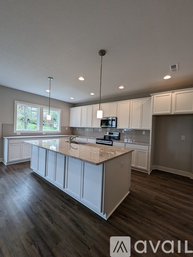 A modern kitchen with a central island and wooden flooring.