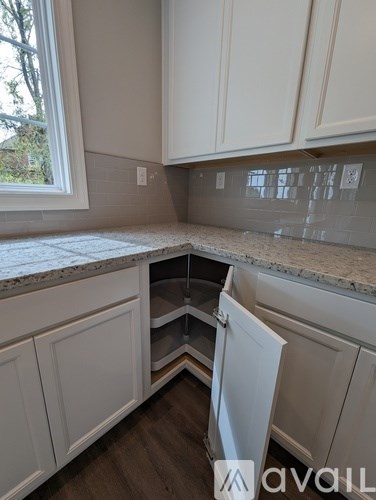 A kitchen with white cabinets and a marble countertop.