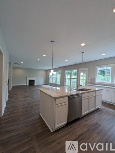 A modern kitchen with wooden floors and white cabinets.