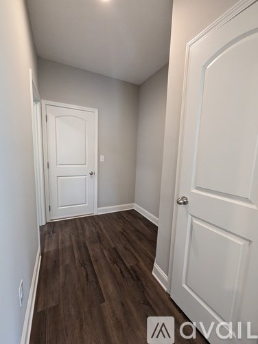 A hallway with a white door and a white wall.