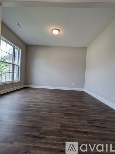 A room with wooden flooring and a window letting in natural light.