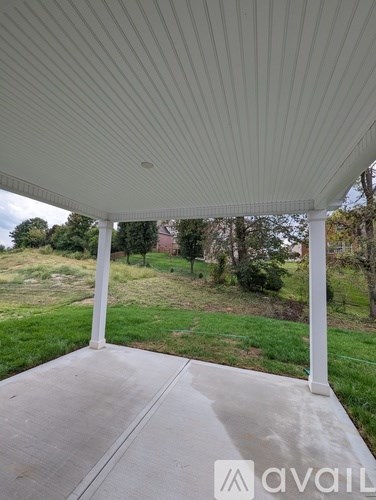 A covered porch with a white ceiling and pillars.