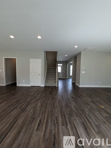 A room with wooden floors and a staircase leading to another room.