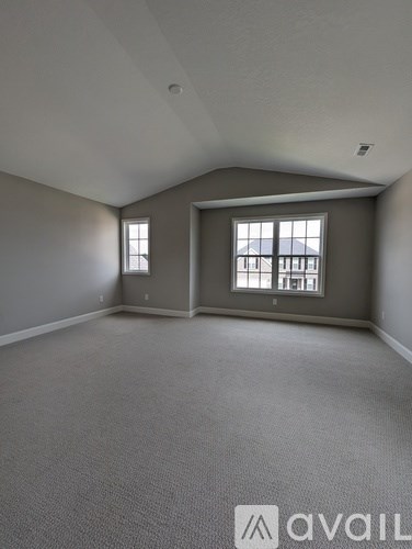 A spacious room with grey carpeting and a large window.