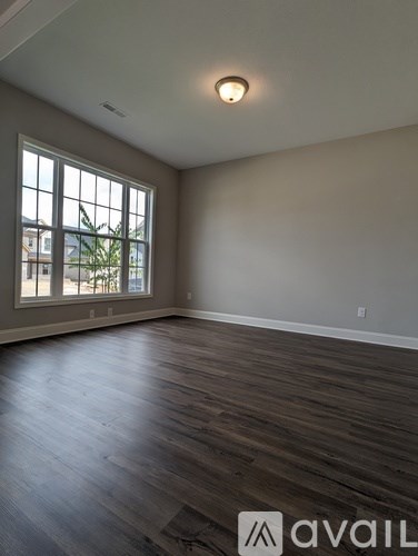 A room with wooden flooring and a large window.
