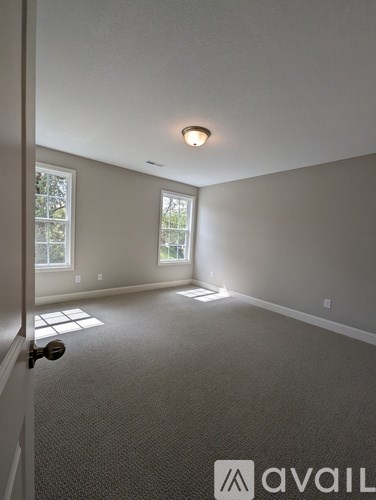 A room with a carpeted floor and a door leading to a window.
