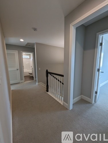 A carpeted hallway with a white railing and a door on the right.