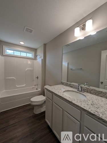 A bathroom with a toilet, sink, and mirror.