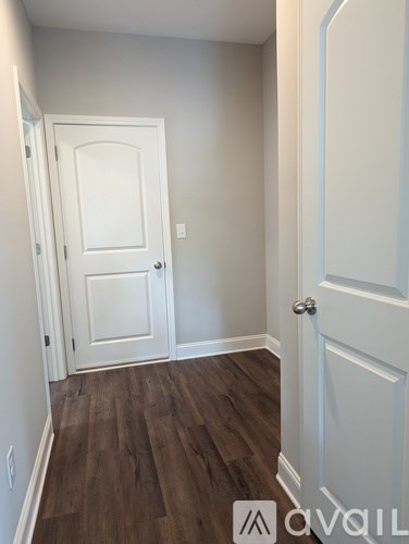 A hallway with a white door and a wooden floor.