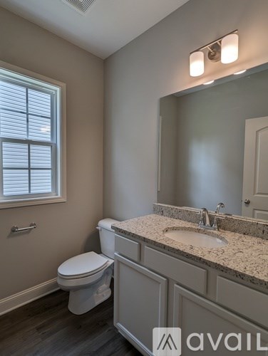A bathroom with a toilet, sink, and mirror.