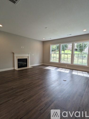 A large empty room with a fireplace and wooden floors.