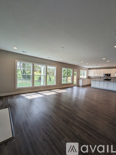 A spacious room with wooden floors and large windows.