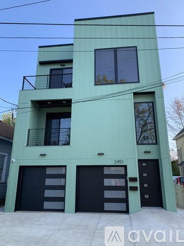 A two-story building with a green facade and black garage doors.