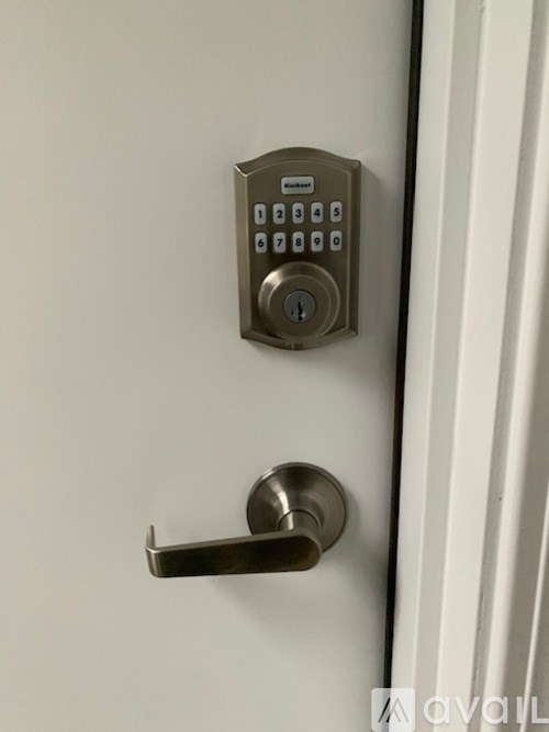 A door handle and a keypad lock on a white door.