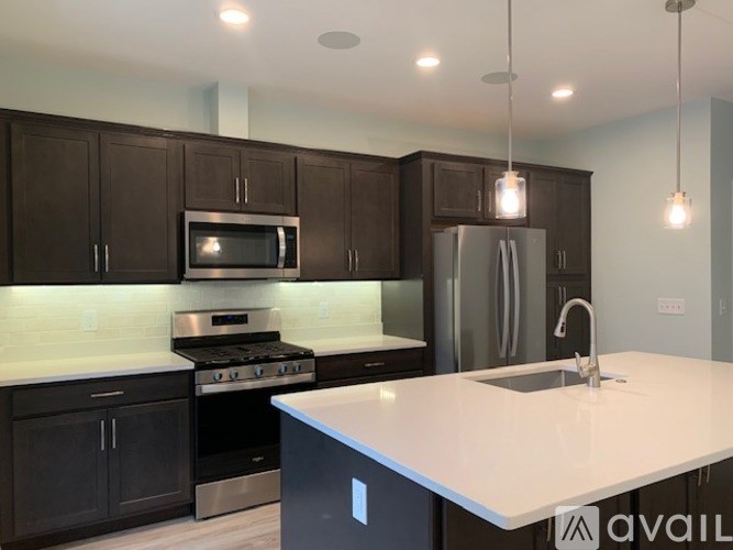 A kitchen with dark brown cabinets and a white countertop.