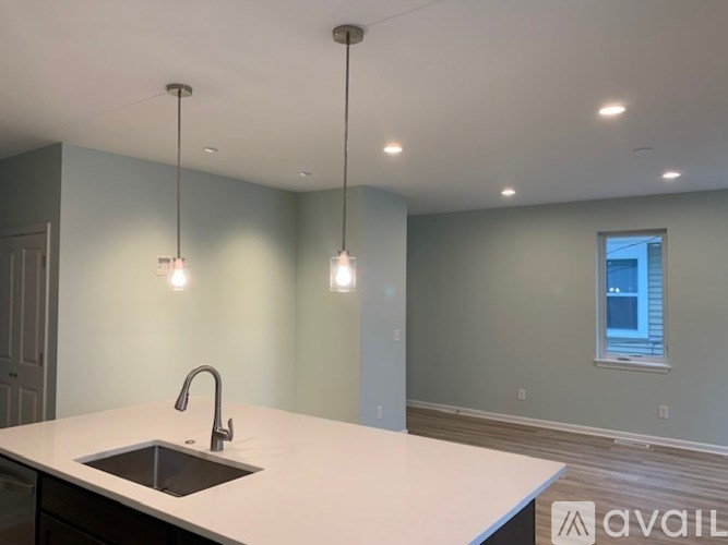 A kitchen with a sink and pendant lights.