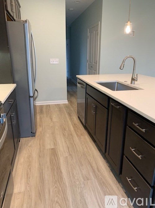 A kitchen with a refrigerator, sink, and cabinets.
