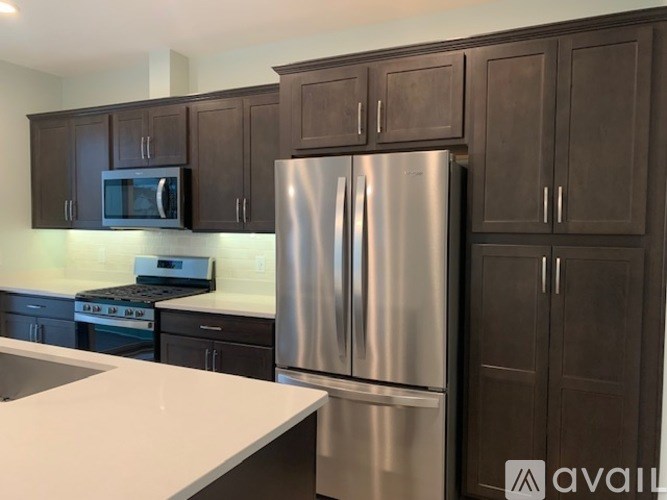 A modern kitchen with a stainless steel refrigerator and dark brown cabinets.