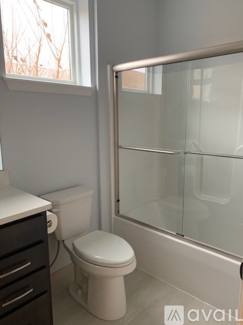 A white toilet sits next to a glass shower door in a bathroom.