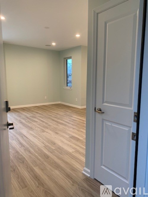 A room with a white door and wooden flooring.