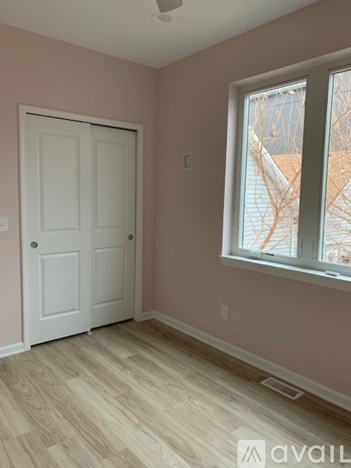 A room with a white door and a window with a view of a tree.